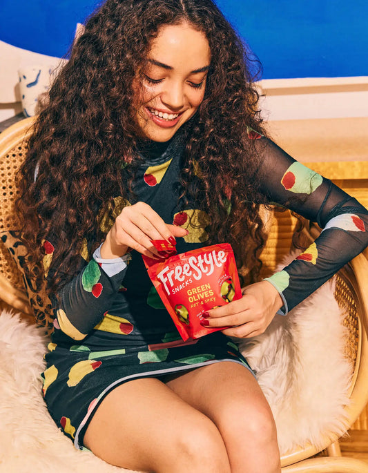 Woman holding a pack of Freestyle Hot & Spicy Green Olives
