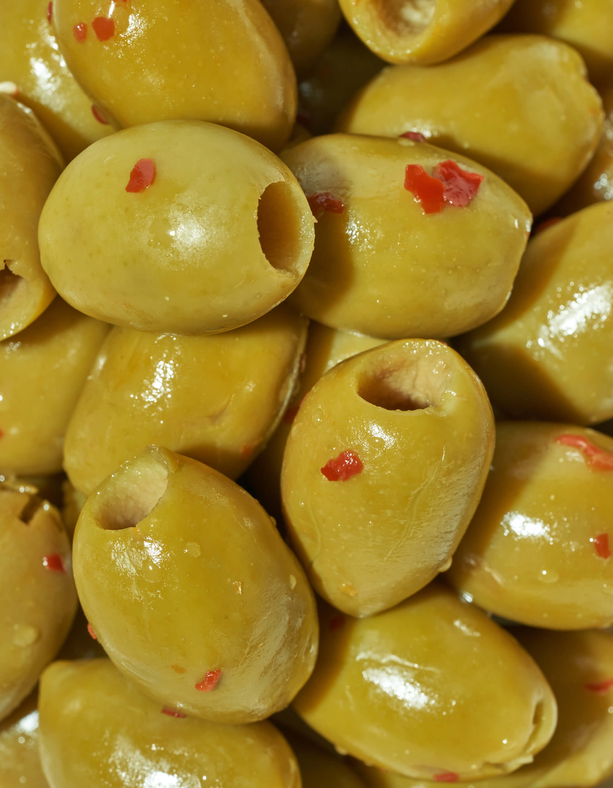 Close-up of green olives with red pepper pieces.