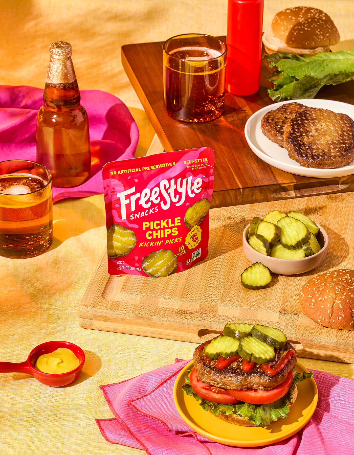 Freestyle Snacks Pickle Chips Kickin' Picks package on a table with burgers and drinks