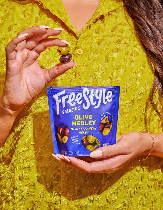 Person holding a Freestyle Snacks Olive Medley packet 