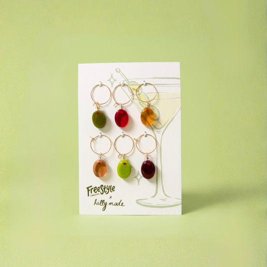 Set of colorful wine glass charms on a card with a green background