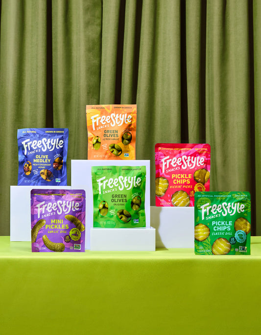 Assorted Freestyle snack packages on a green surface with a green curtain background