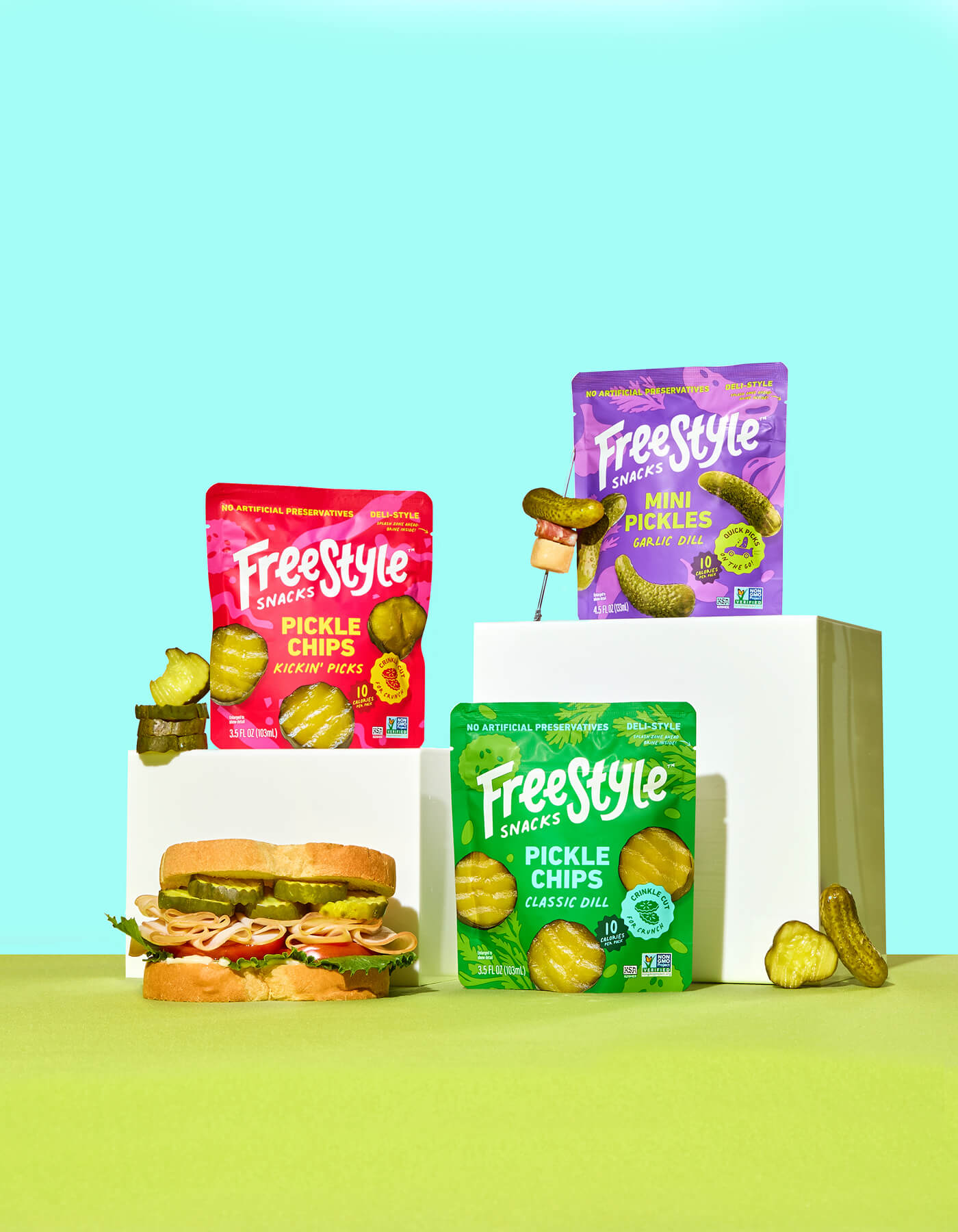 Freestyle Pickle Chips Kickin' Picks packaging, Freestyle Mini Pickles Garlic Dill packaging, Freestyle Pickle Classic Dill packaging on a green and blue gradient background